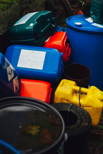 A collection of green cleaning supplies arranged on a bright green background, including a spray bottle with a trigger nozzle, a plastic bottle with a green cap, a sponge with a cleaning handle, a jar
